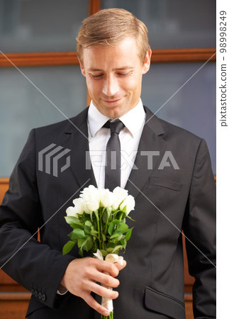 Love, romantic and man with flowers for valentines day, romance or gesture while standing against a wall background. Roses, happy and gentleman with bouquet for sweet, anniversary gift or first date 98998249