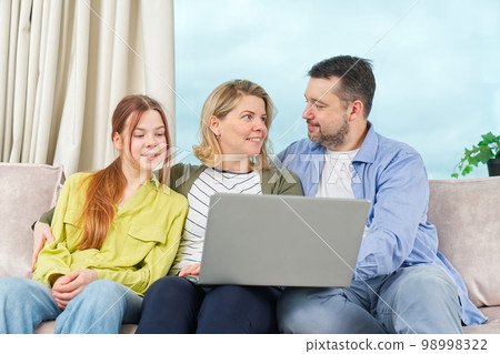 Happy Family on couch using gadget. Rest at home. Using Digital devices at home 98998322