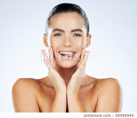 Beauty, face and skincare portrait of a woman in studio with natural glow skin and white teeth. Aesthetic model person biting on tongue for facial dermatology and spa wellness on a bright background 98998948