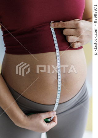 Pregnancy. Pregnant woman measuring belly. Healthy pregnancy. Baby bump of pregnant woman close-up. Concept image of prenatal care, maternity, health, medicine and gynecology at obgyn Pregnancy. Pregnant woman measuring belly. Healthy pregnancy. Baby bump of pregnant woman close-up. Concept image of prenatal care, maternity, health, medicine and gynecology at obgyn 98998971