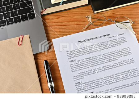 一張虛擬的英文相互保密協議放在桌子上，上面放著筆和筆記本 98999895