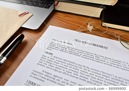 A dummy English sales contract sits on a desk with pens and notebooks 98999900