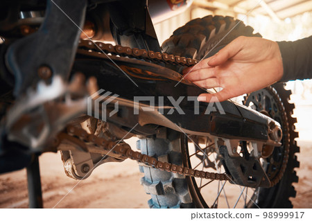 Hands, mechanic and motorbike chain in repairs working on springs or timing for safety or mechanical parts. Hand of engineer fixing bike, transport or transmission on automobile or gears in workshop 98999917