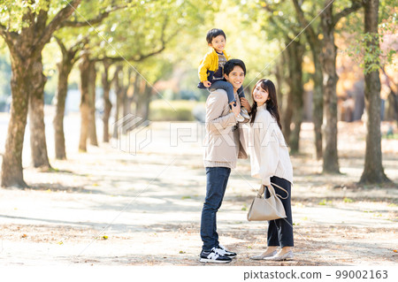 A family walking with a child on their shoulders 99002163
