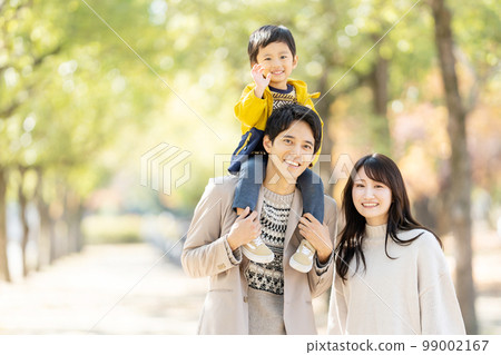 A family walking with a child on their shoulders 99002167