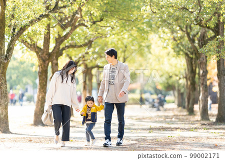 一家人手拉手走在綠樹成蔭的街道上 99002171