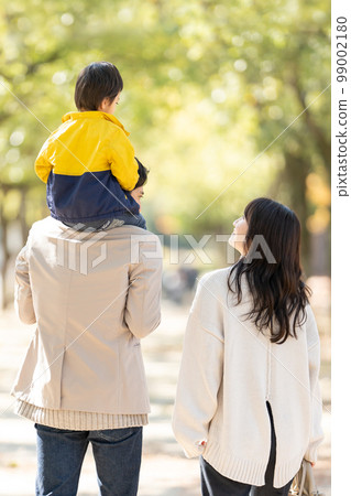 Rear view of a family walking with a child on their shoulders Rear view of a family walking with a child on their shoulders 99002180