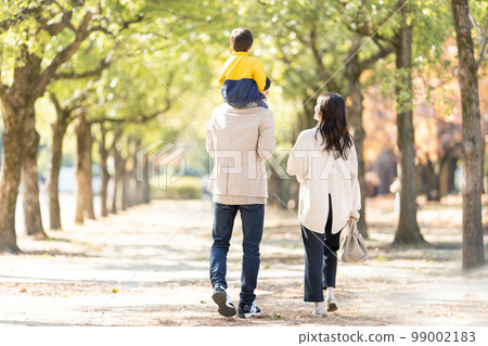 Rear view of a family walking with a child on their shoulders 99002183