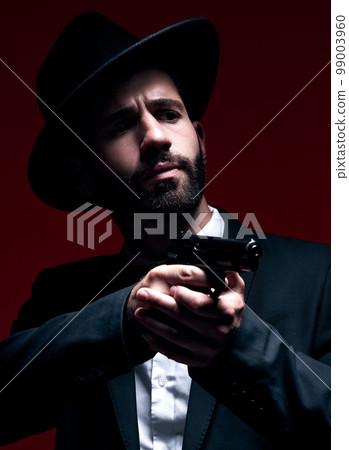 Assassin, suit or shooting weapon on studio background in dark secret spy, isolated mafia leadership or crime security. Model, gangster or hitman gun in aim, formal style or fashion clothes aesthetic 99003960