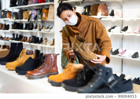 Asian woman in a mask chooses autumn halfboots Asian woman in a mask chooses autumn halfboots 99004053