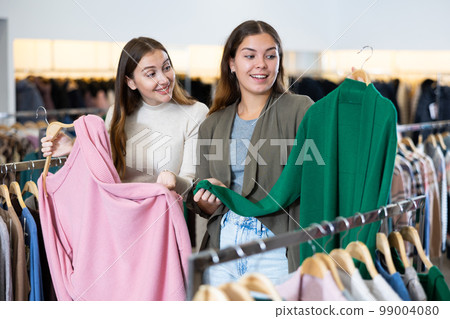 Female friends choosing warm cardigan in store Female friends choosing warm cardigan in store 99004080