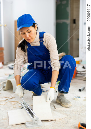 Woman repairer using tile cutter indoors 99004447