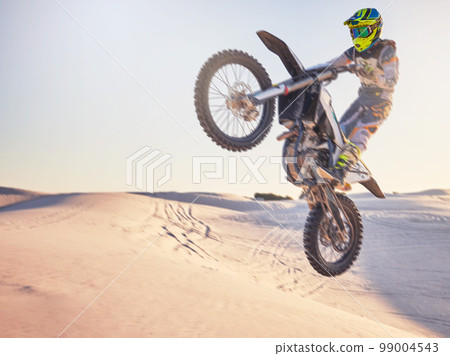 Motorcycle jump, sports outdoor with exercise in desert, stunt for extreme sport, speed and helmet for safety. Challenge, freedom and athlete biking, fitness mockup and person training with dirt bike Motorcycle jump, sports outdoor with exercise in desert, stunt for extreme sport, speed and helmet for safety. Challenge, freedom and athlete biking, fitness mockup and person training with dirt bike 99004543