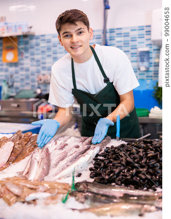 Positive salesman demonstrating lucet fish in fish store Positive salesman demonstrating lucet fish in fish store 99004658