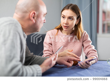 Wife and husband with smartphones having conversation 99004868
