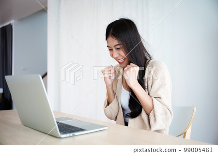 Funny euphoric young asian woman celebrating winning Funny euphoric young asian woman celebrating winning 99005481