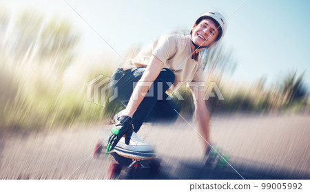 Skateboard, blurred motion and fast with a sports man skating on an asphalt road outdoor for recreation. Skate, soft focus and speed with a male athlete or skater training outside on the street 99005992