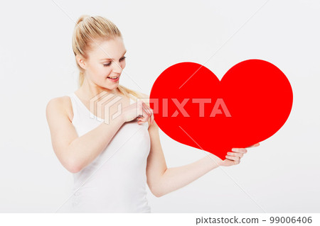 Valentines day, happy and woman with a heart in a studio with a smile for a romantic gesture. Happiness, excited and female model from Australia holding a love shape isolated by a white background. 99006406