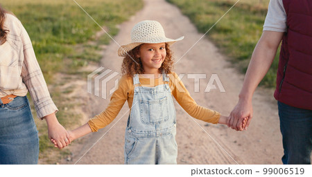 Family, farm and agriculture with a girl holding hands with her parents on a sand road in a field or meadow. Sustainability, love and summer with a daughter hand in hand with her mother and father 99006519