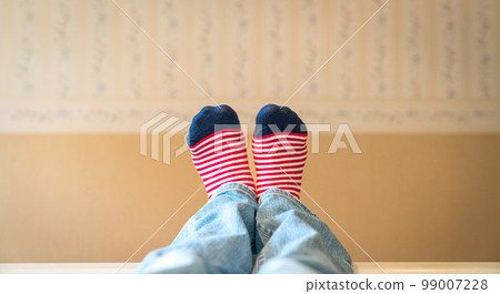 Woman's feet with colorful socks resting on bed. 99007228
