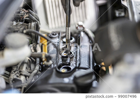 Mechanic changing spark plugs in car 99007496