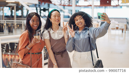 Selfie, friends and social media with woman together posing for a photograph in a mall or shopping center. Phone, social media and smile with a happy female friend group taking a picture for fun 99007716