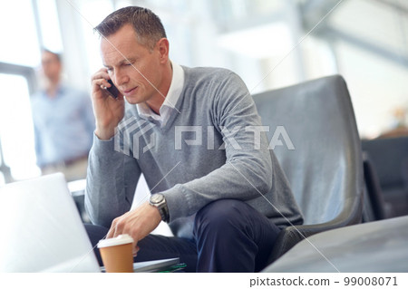 Phone call, communication or business man in airport lobby for loan, wealth or investment negotiation. Travel, laptop or manager with smartphone for networking, b2b network or planning meeting 99008071