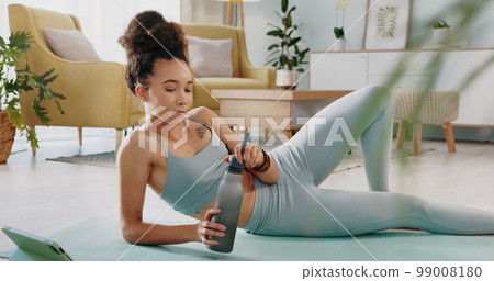 Fitness, relax and woman drinking water in living room with tablet streaming online class for workout, health and exercise. Yoga, internet or e learning with athlete in home gym training for wellness Fitness, relax and woman drinking water in living room with tablet streaming online class for workout, health and exercise. Yoga, internet or e learning with athlete in home gym training for wellness 99008180