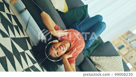 Headphones, listening and dance of black woman on a sofa excited for subscription service, technology and home connection. Happy, relax and girl portrait dancing on couch while listening to music app 99008230