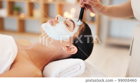 Skincare, beauty and spa facial with woman face mask at a wellness, health and salon. Relax, luxury and and girl resting while beautician hands apply exfoliation, peeling and hydration skin product Skincare, beauty and spa facial with woman face mask at a wellness, health and salon. Relax, luxury and and girl resting while beautician hands apply exfoliation, peeling and hydration skin product 99008460