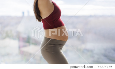 Pregnant woman belly in profile. Healthy pregnancy concept image of beautiful expectant mother showing baby bump in closeup 99008776