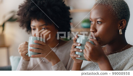 Chocolate drink and black woman friends on sofa talking and having winter celebration. African people or gen z women enjoying sweet milk coffee or cocoa beverage on couch in their apartment lounge Chocolate drink and black woman friends on sofa talking and having winter celebration. African people or gen z women enjoying sweet milk coffee or cocoa beverage on couch in their apartment lounge 99008938