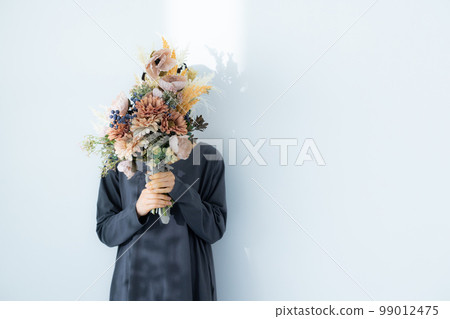 A woman in a gray dress holding a bouquet 99012475