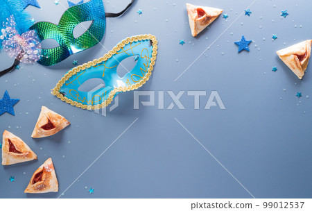 Happy Purim carnival decoration concept made from mask and sparkle star and hamantaschen cookies on pastel background. (Happy Purim in Hebrew, jewish holiday celebrate) 99012537