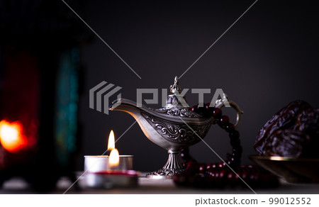 Ramadan food and drinks concept. Ramadan Lantern with arabian lamp, wood rosary, tea, dates fruit and lighting on a wooden table with dark background. Ramadan food and drinks concept. Ramadan Lantern with arabian lamp, wood rosary, tea, dates fruit and lighting on a wooden table with dark background. 99012552