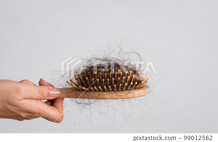 Woman hand holding a comb with hair loss on white background. Health care and medical, Hair loss problem concept. 99012562