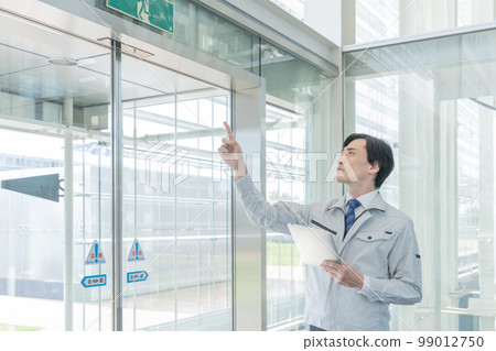 A man in work clothes inspecting a building A man in work clothes inspecting a building 99012750