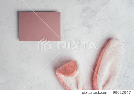 Easter composition of pink post paper card on white background and cutting out bunny rabbit toy fluffy hair ears. Easter composition of pink post paper card on white background and cutting out bunny rabbit toy fluffy hair ears. 99012947