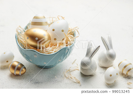 Decorative rabbits and a bowl with Easter eggs on the table 99013245