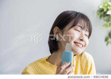 Young woman using water peeler at home 99014696