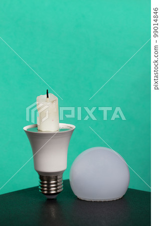 Light bulb with candle stub. Global ecology, International Energy Saving Day or Earth Hour concept. On a turquoise background. Light bulb with candle stub. Global ecology, International Energy Saving Day or Earth Hour concept. On a turquoise background. 99014846