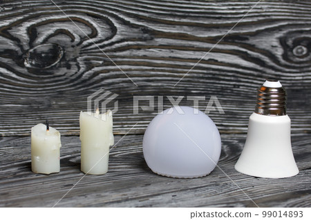 Disassembled LED bulb. Nearby is a candle stub. Global ecology, International Day of Energy Saving or Earth Hour concept. Against the background of black boards. Disassembled LED bulb. Nearby is a candle stub. Global ecology, International Day of Energy Saving or Earth Hour concept. Against the background of black boards. 99014893