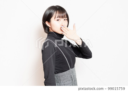 Young woman covering her mouth with her hand Young woman covering her mouth with her hand 99015759