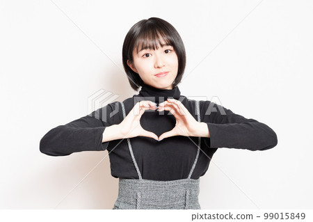 Young woman showing a heart shape with her hands 99015849