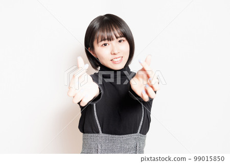 Young woman showing a heart shape with her hands 99015850