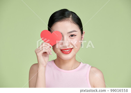 pretty Asian woman with toothy smile while holding Valentines Day card in hands, pretty Asian woman with toothy smile while holding Valentines Day card in hands, 99016558