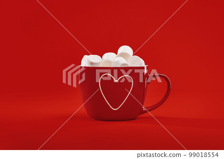 Red gift hot chocolate mug with heart and marshmallows on red background. Happy St Valentines sweet gift. Thank you. Mothers Day. Love concept monochrome 99018554