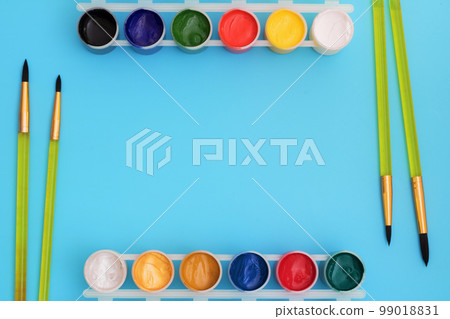 Colorful paints in jars on a blue background near the brushes. Color palette. Concept-creativity and school theme. Colorful paints in jars on a blue background near the brushes. Color palette. Concept-creativity and school theme. 99018831