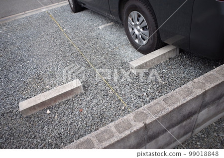 A black car parked in a gravel parking lot 99018848