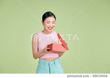Emotional brunette young woman opens gift box, having overjoyed ecstatic facial expression 99019408